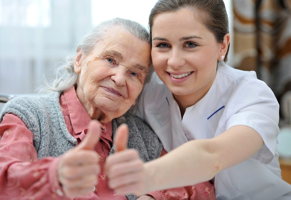 hospice nurse and elderly patient giving thumbs up