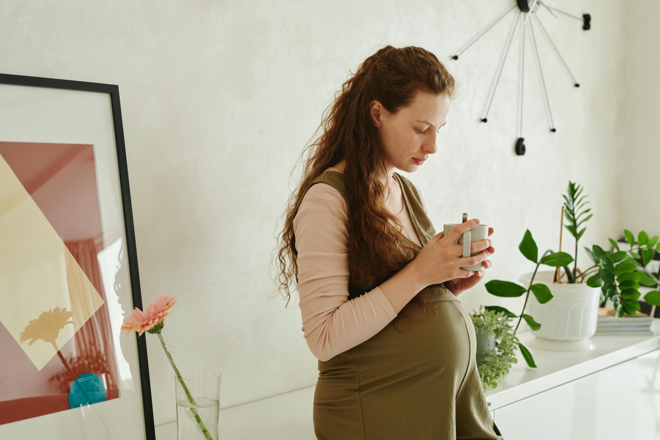 pregnant woman in a green dress holding a cup