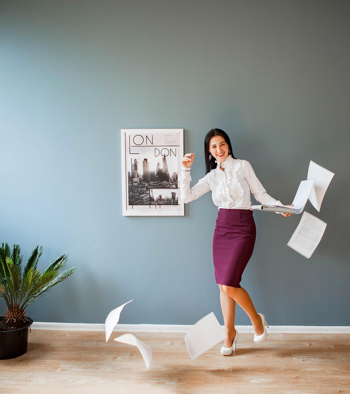 A joyful professional woman smiling and tossing papers in the air, symbolizing confidence, celebration, and personal achievement.